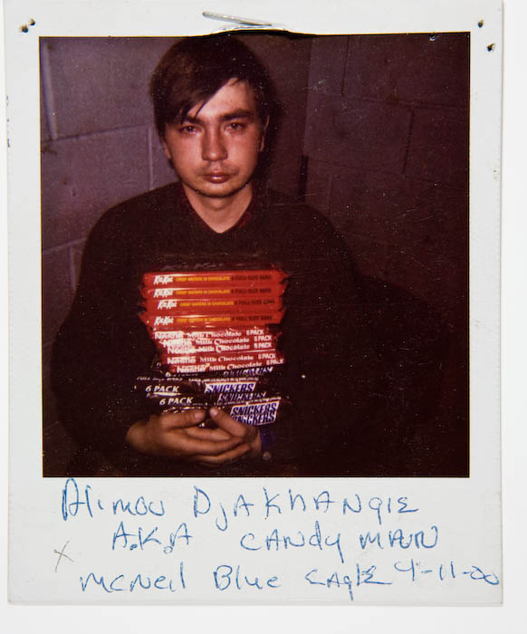Young man in a black sweatshirt holding a neat stack of candy multipacks: Kit Kat, Nestle milk chocolate and Snickers.