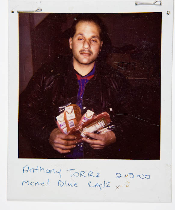 Man in a black leather jacket holding several packages of meat and boxed groceries.