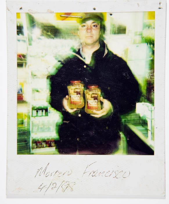 Blurred, double-exposed photo of a man in a cap and dark coat holding two jars of Taster's Choice instant coffee in a store aisle.
